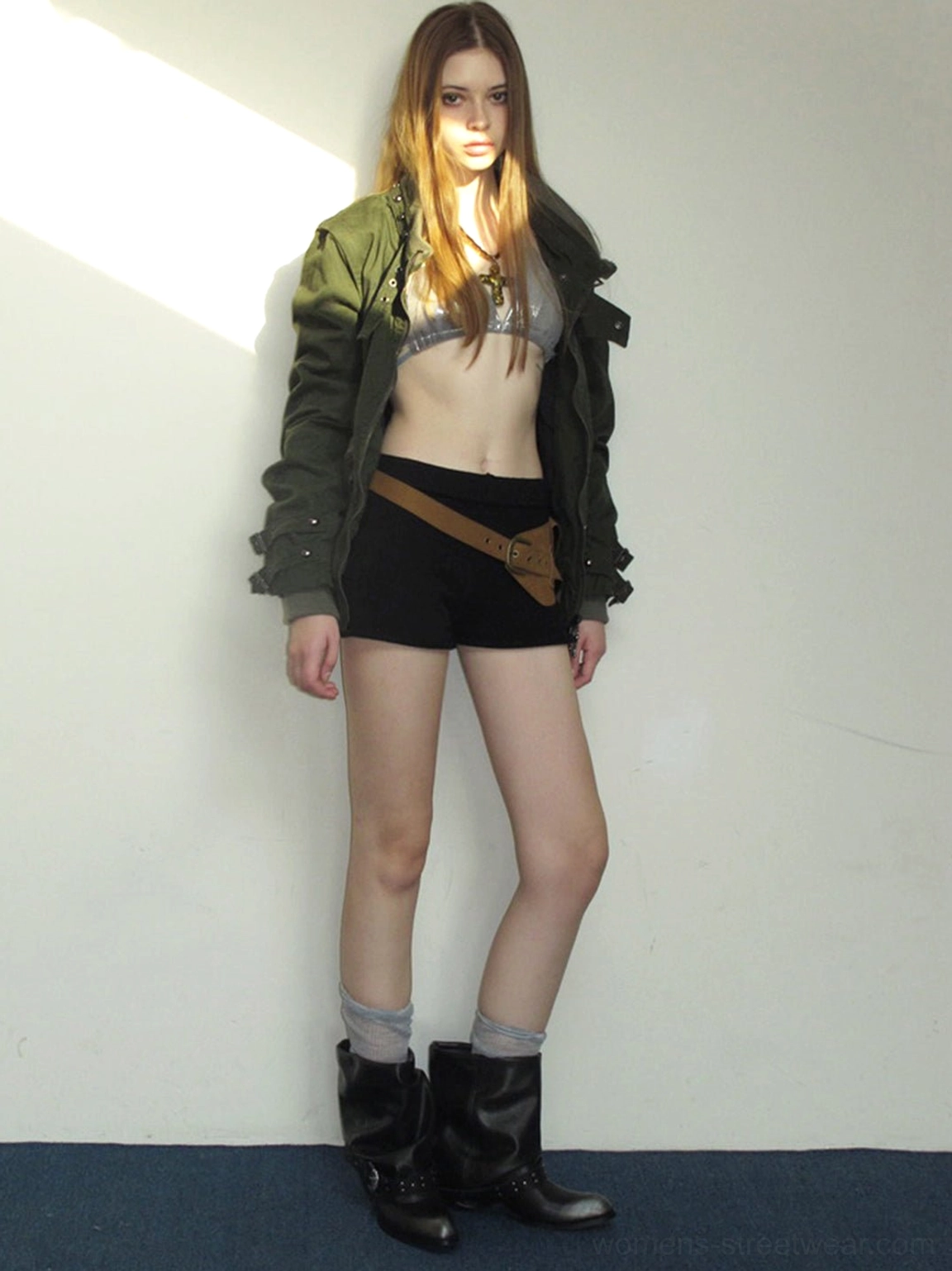 Side profile of black buckle chunky ankle boots styled with shorts and silver top