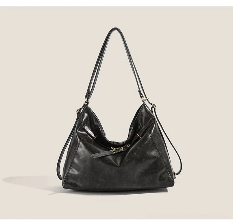 Matte black buckle detail hobo shoulder bag shown from a front three-quarter angle with decorative straps, gold-tone hardware, and relaxed Y2K streetwear silhouette
