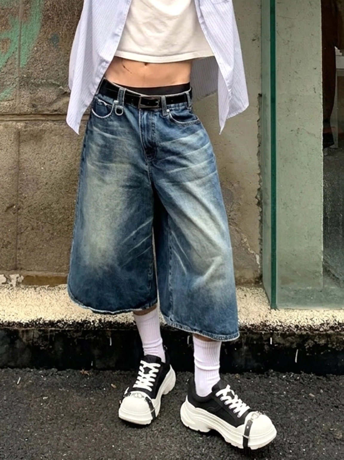 Male streetwear outfit styled with black buckle platform sneakers, white ankle socks, baggy denim culottes, and relaxed shirt