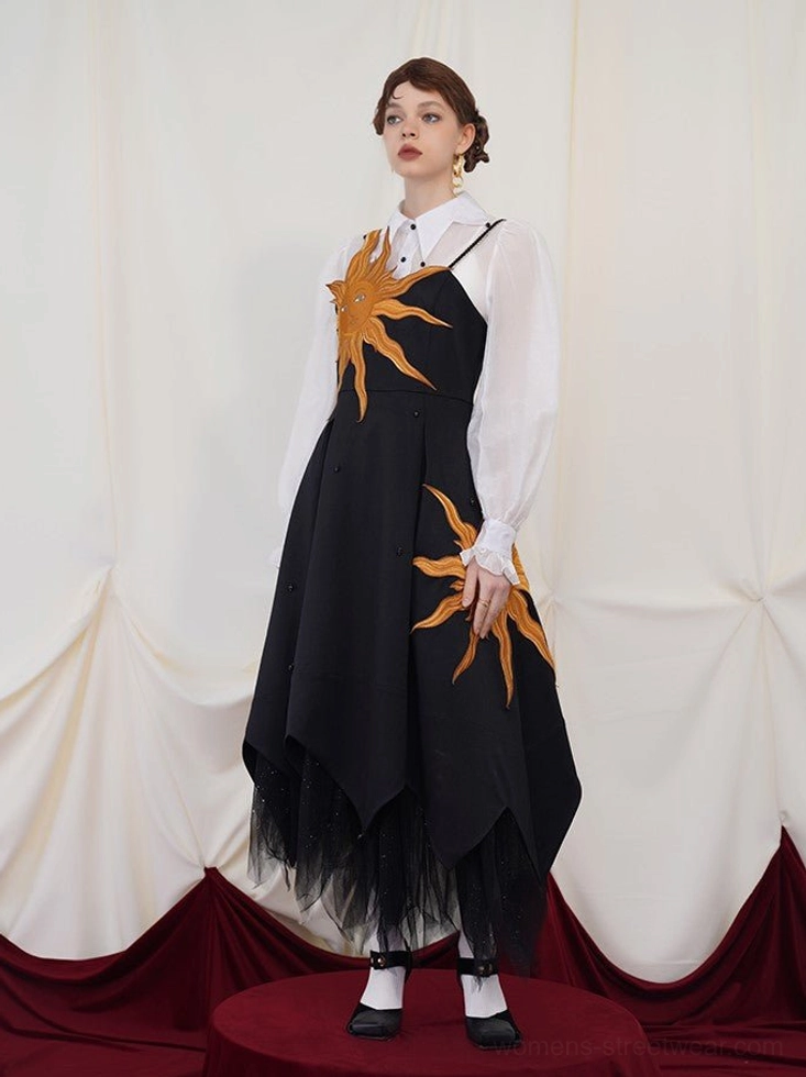 Full front view of a black camisole maxi dress with two golden sun embroideries styled with a sheer white blouse