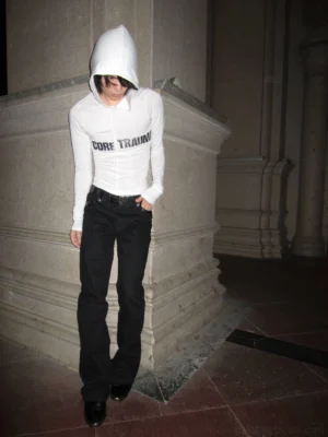Black canvas leather-trim flare trousers styled with a white hooded long-sleeve top in a classical stone interior