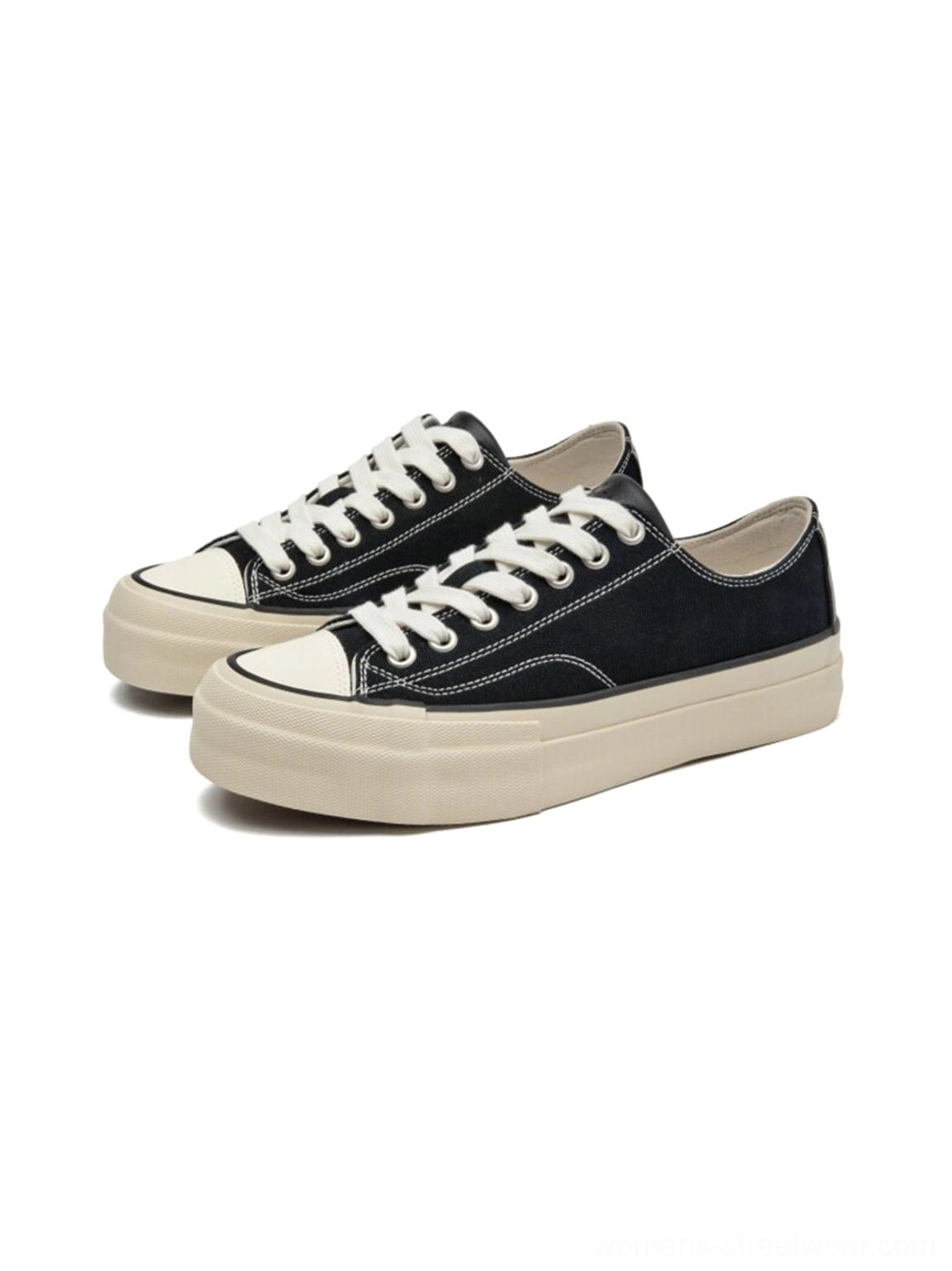 Right side oblique view of two black canvas low-top platform sneakers with cork midsole, showing white contrast stitching and minimal design