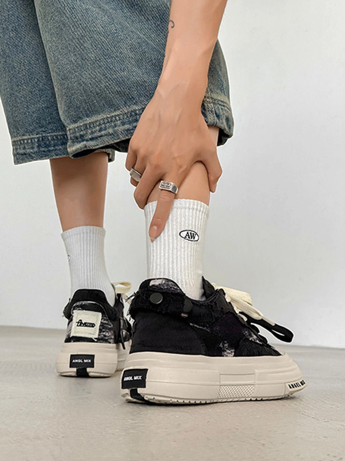 Rear low angle view of black canvas platform sneakers styled with cropped denim jeans and white crew socks