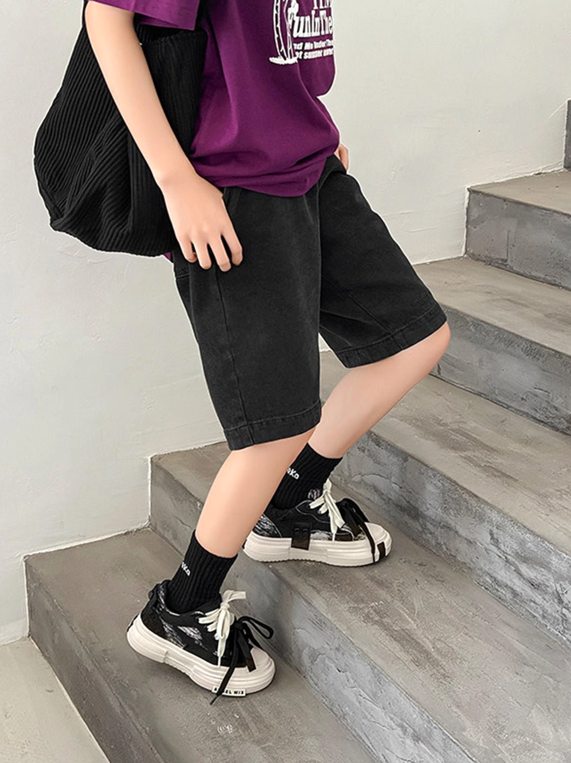 Female streetwear outfit featuring black canvas platform sneakers, black denim shorts, purple tee, and black crew socks