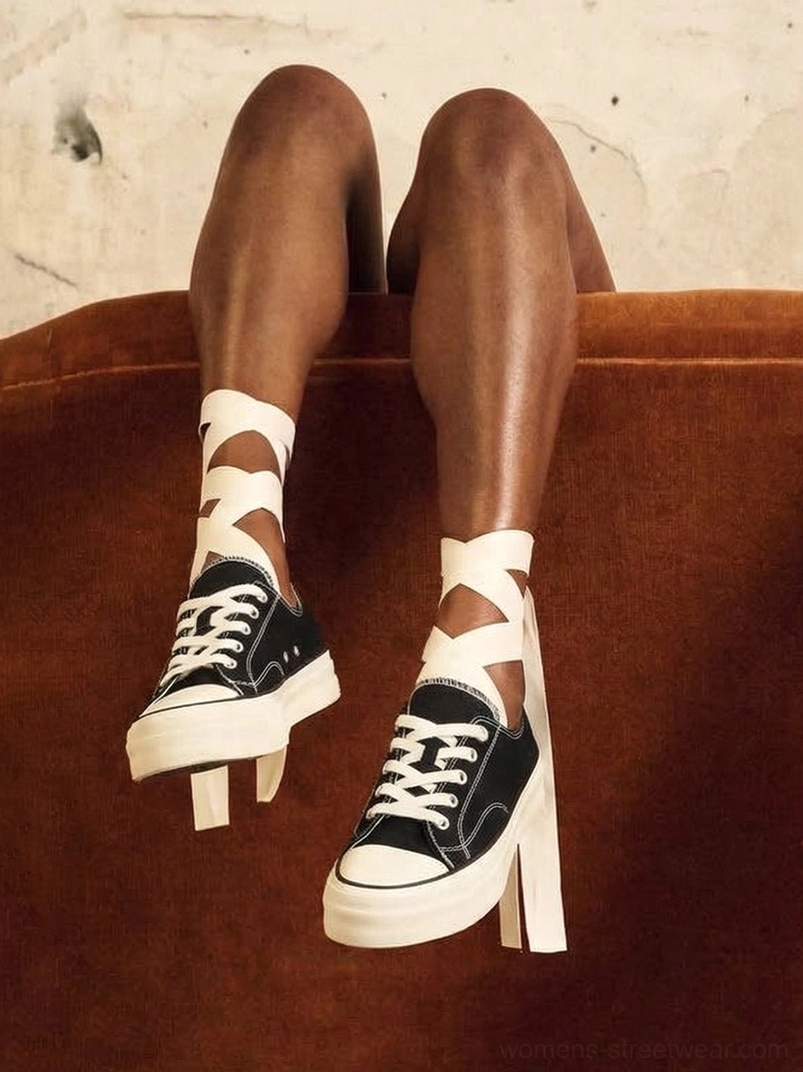 Female model wearing black canvas platform sneakers with white laces and ribbon cross-strap socks in indoor streetwear styling