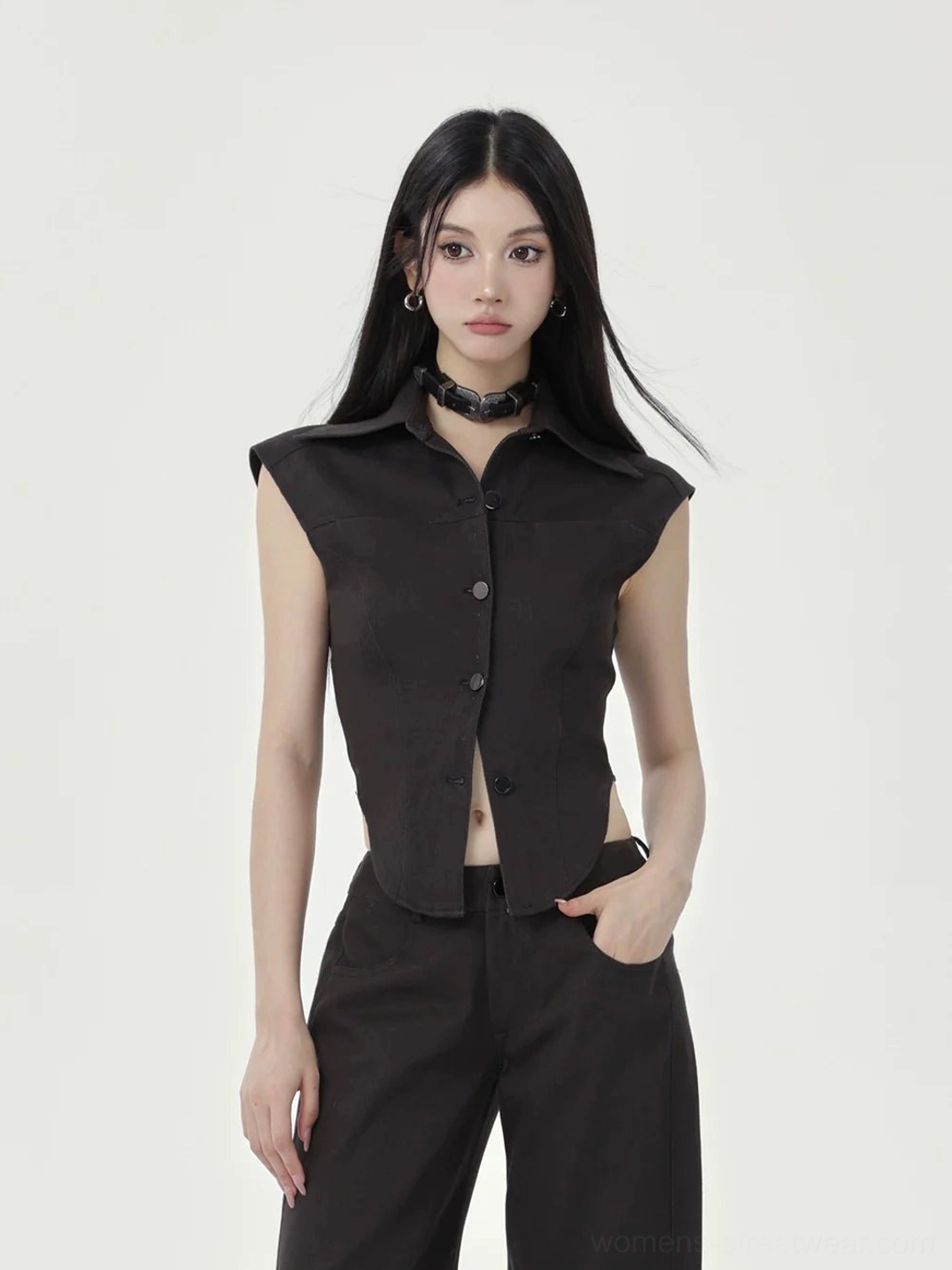 Black cap sleeve cropped button-up top styled with wide-leg trousers in a front-facing minimalist studio streetwear look