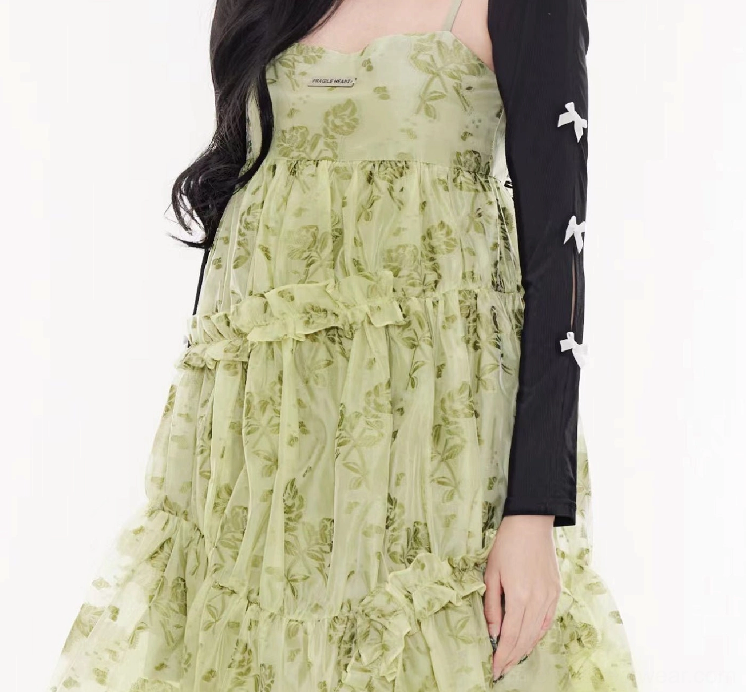 Close-up of black cardigan sleeves with hollow-out slits and contrasting white bow details over a floral dress