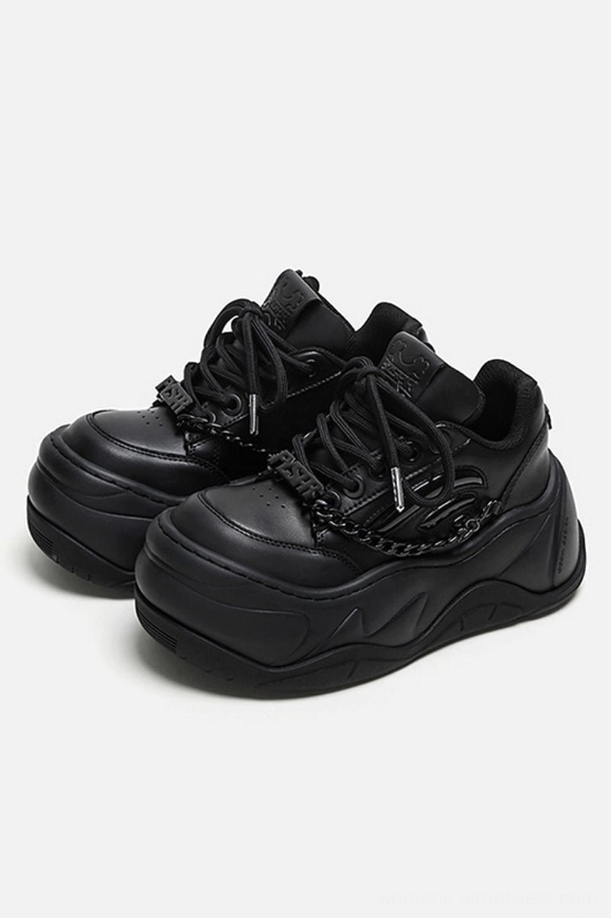 Front three-quarter view of matching black platform sneakers with lace-up closure, silver chain vamp trim, and bold chunky wave soles