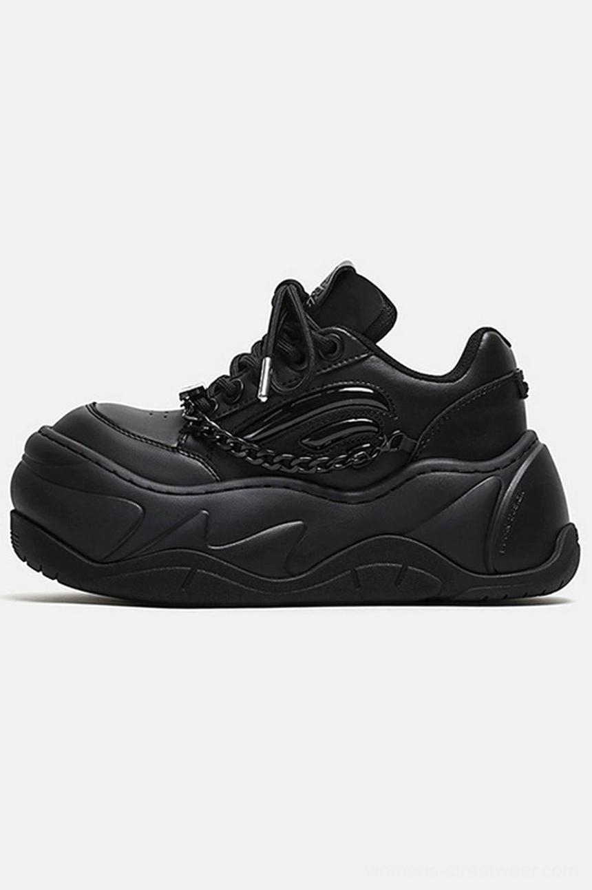 Left side profile of all-black chain platform wave sneakers with matte cowhide leather upper, chunky sculpted rubber sole, and metal vamp decoration