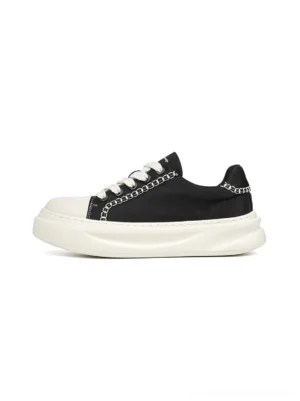 Black chain-trim contrast-stitch platform sneaker shown from a left side three-quarter view with black canvas upper white toe cap thick sole and flat white laces