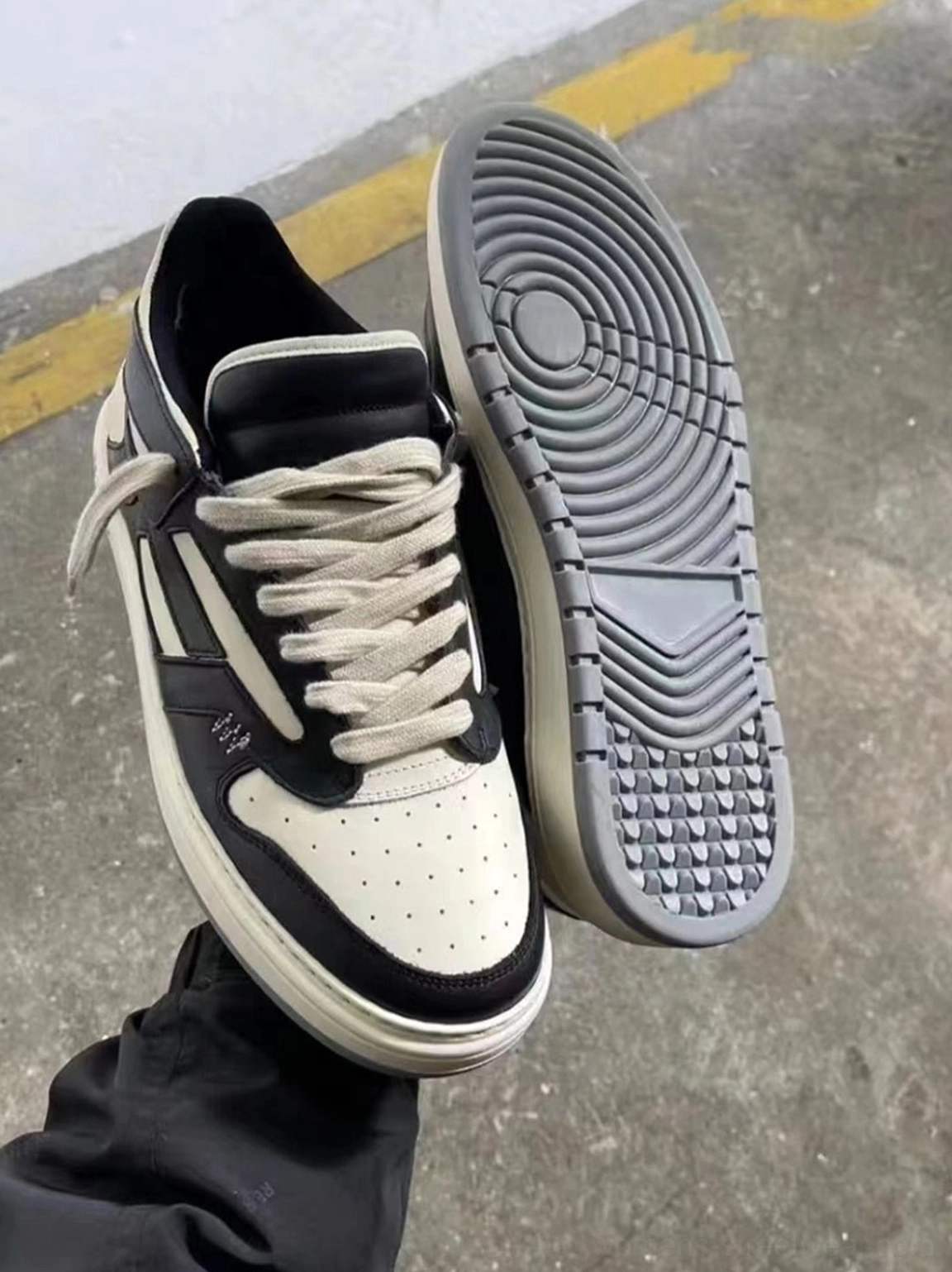 Flat lay of black charcoal and off-white suede-look low-top sneakers showing perforated toe textured outsole and stitching