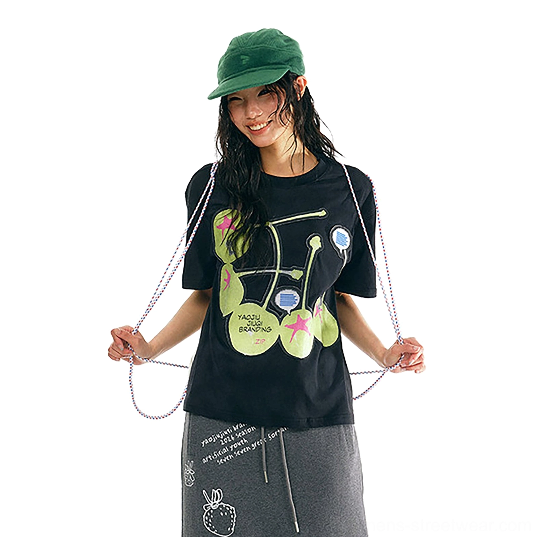 Black cherry pop graphic cotton streetwear t-shirt front view styled with green camp cap and grey strawberry print sweatpants