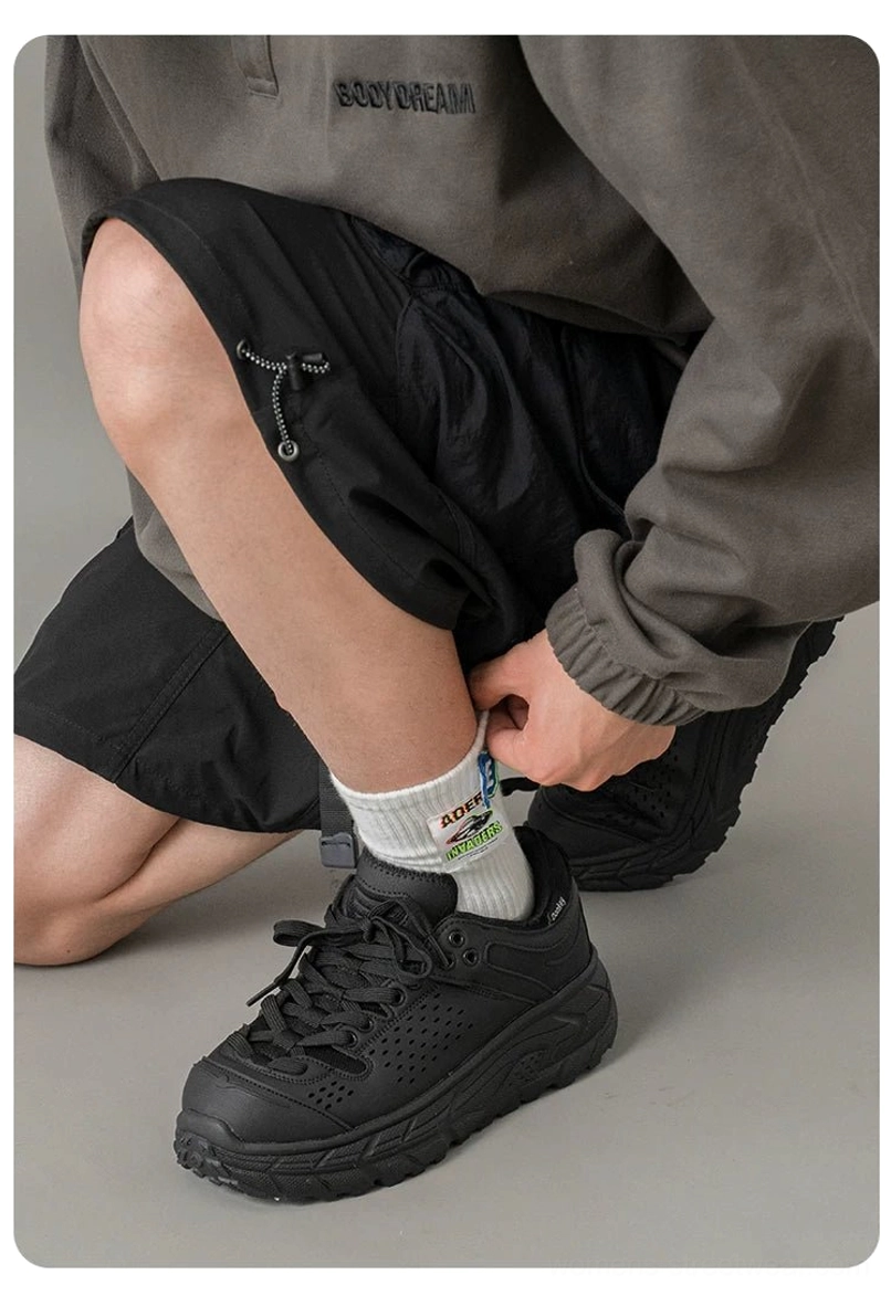 Side view of black chunky hiking sneakers worn with utility workwear, highlighting the breathable perforated upper and deep anti-slip outsole tread