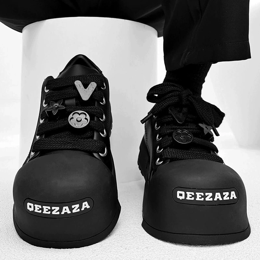 Black chunky lace-up platform sneakers close-up with smiley star and geometric decorative lace charms