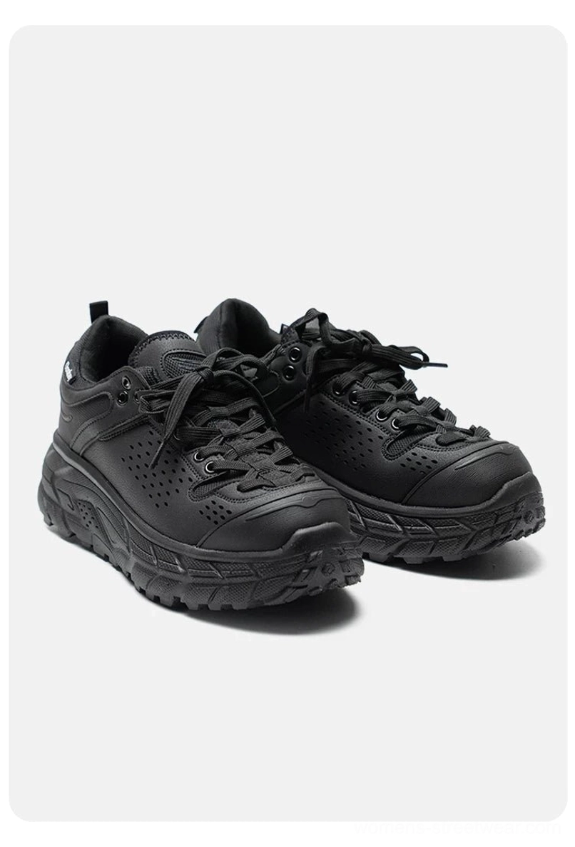 Pair of black chunky outdoor trainers on a neutral gray background, showing the rugged workwear silhouette and detailed EVA traction outsole