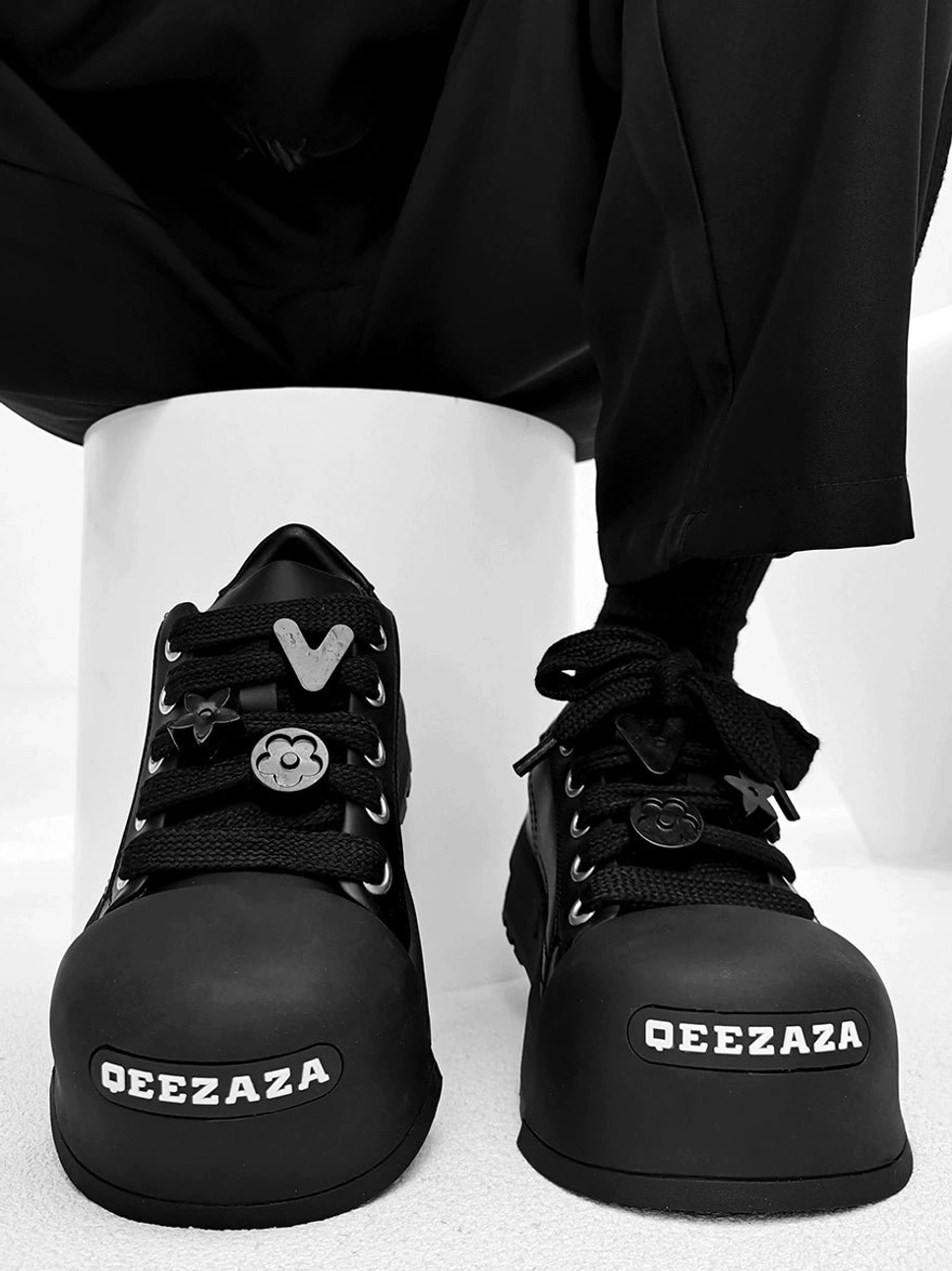 Black chunky platform lace charm sneakers shown from a front top view with oversized rounded toe and thick rubber sole