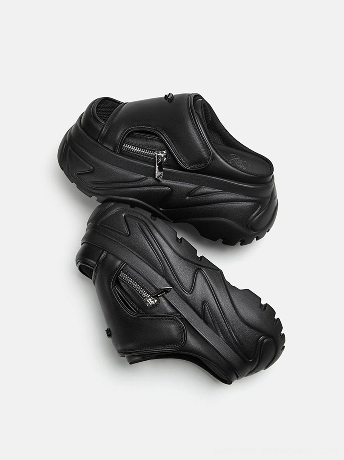Black chunky platform slide sandals shown at an angled view with rugged sporty outsole tread, silver zipper details, and modern techwear-inspired construction