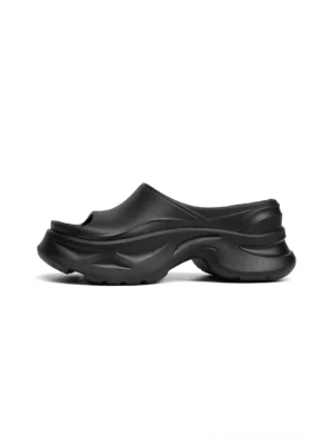 Black chunky platform slide sandal in left side profile showing the thick layered wave sole and open toe streetwear silhouette