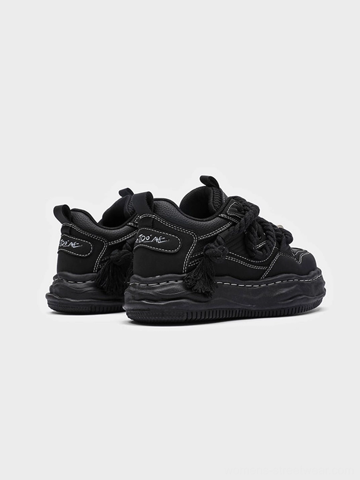 Black chunky platform sneaker detail showing elevated wavy outsole rounded upper and tonal streetwear styling