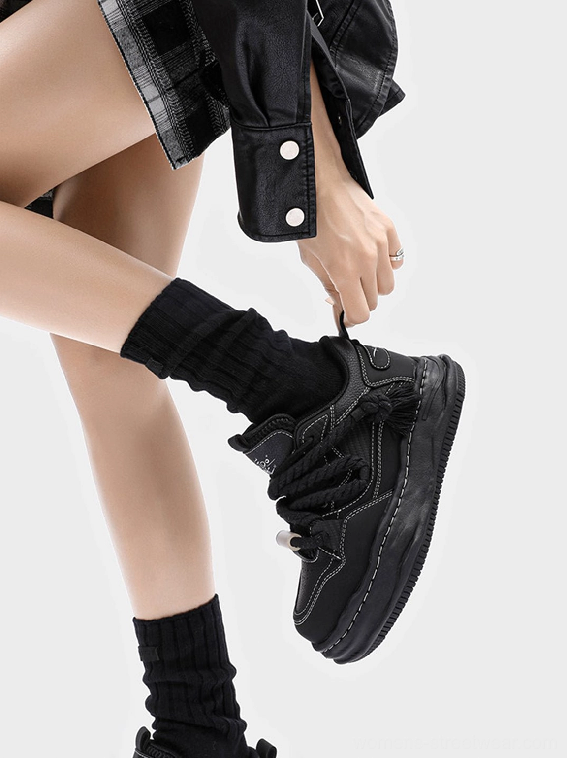 Black chunky platform sneaker viewed from the heel with tassel detail and thick sculpted wavy sole