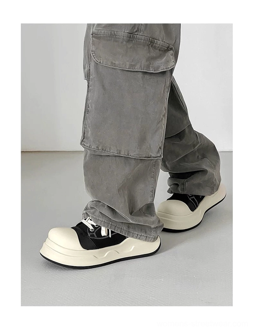 Side on-foot view of black chunky platform sneakers with grey cargo pants highlighting the elevated 4 cm thick sole and oversized rounded silhouette