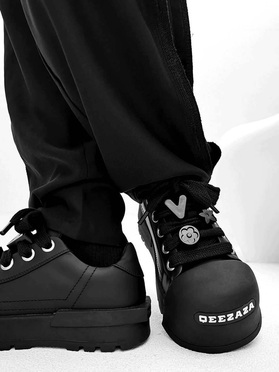 Black chunky platform sneakers back three quarter view showing matte upper thick platform outsole and smiley lace charm