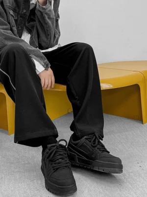 Black chunky platform sneakers styled with a dark denim jacket and wide-leg black pants in a contemporary Korean streetwear outfit