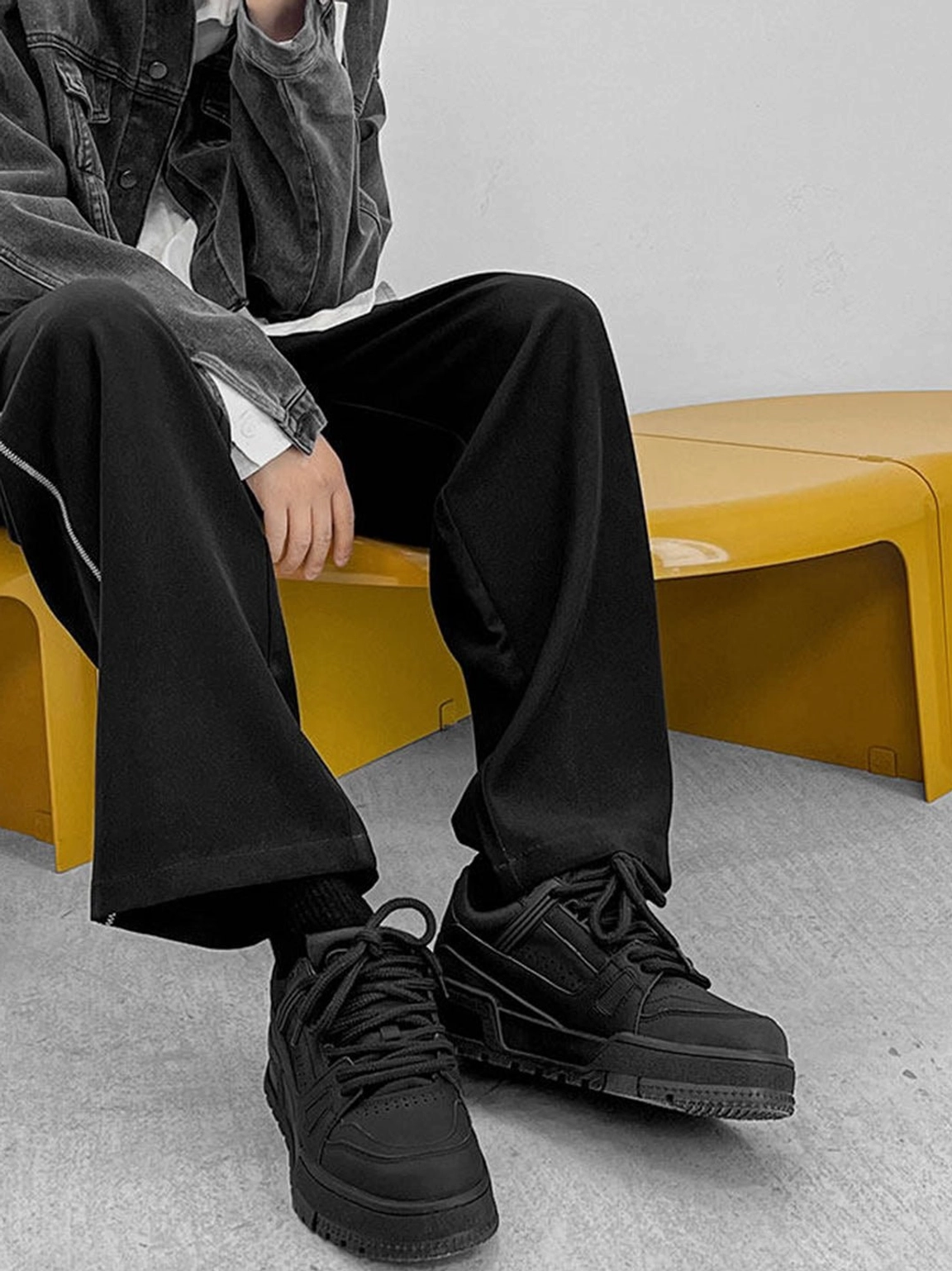 Black chunky platform sneakers styled with a dark denim jacket and wide-leg black pants in a contemporary Korean streetwear outfit