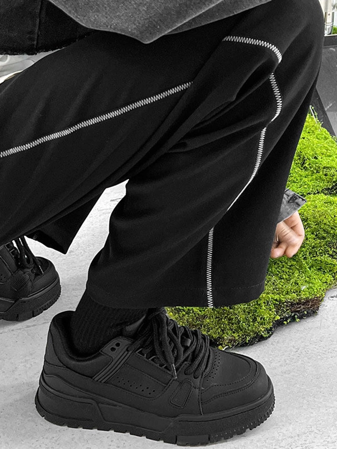 Close angled view of black chunky platform sneakers showing perforated toe panels classic laces and thick rugged rubber outsole