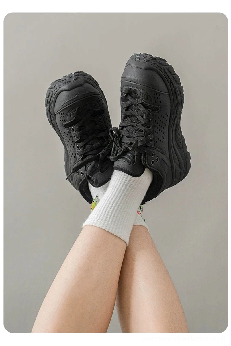 Black chunky utility trainers worn with white crew socks, showing the thick height-enhancing EVA platform and full monochrome streetwear design