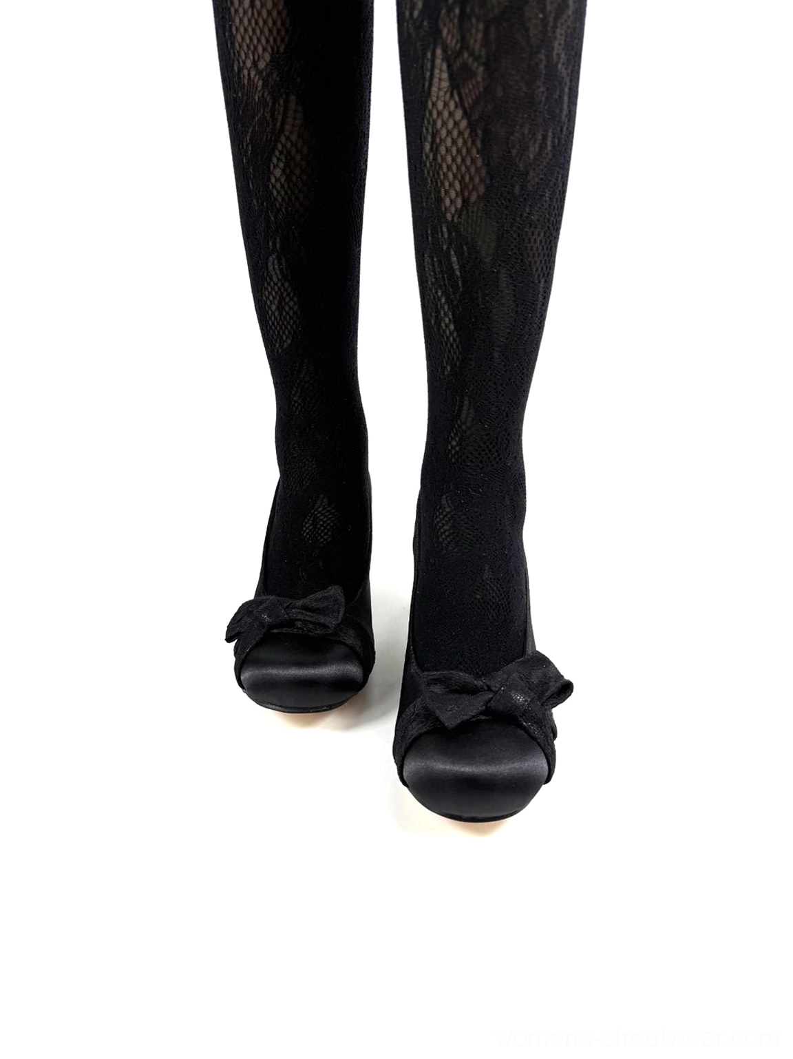 Black closed-toe bow pumps styled with sheer black stockings showing the rounded vamp and decorative front bow