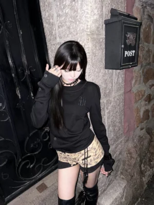 Black coffin cross layered deconstructed long sleeve tee worn by female model in a nighttime streetwear outfit, front three-quarter view
