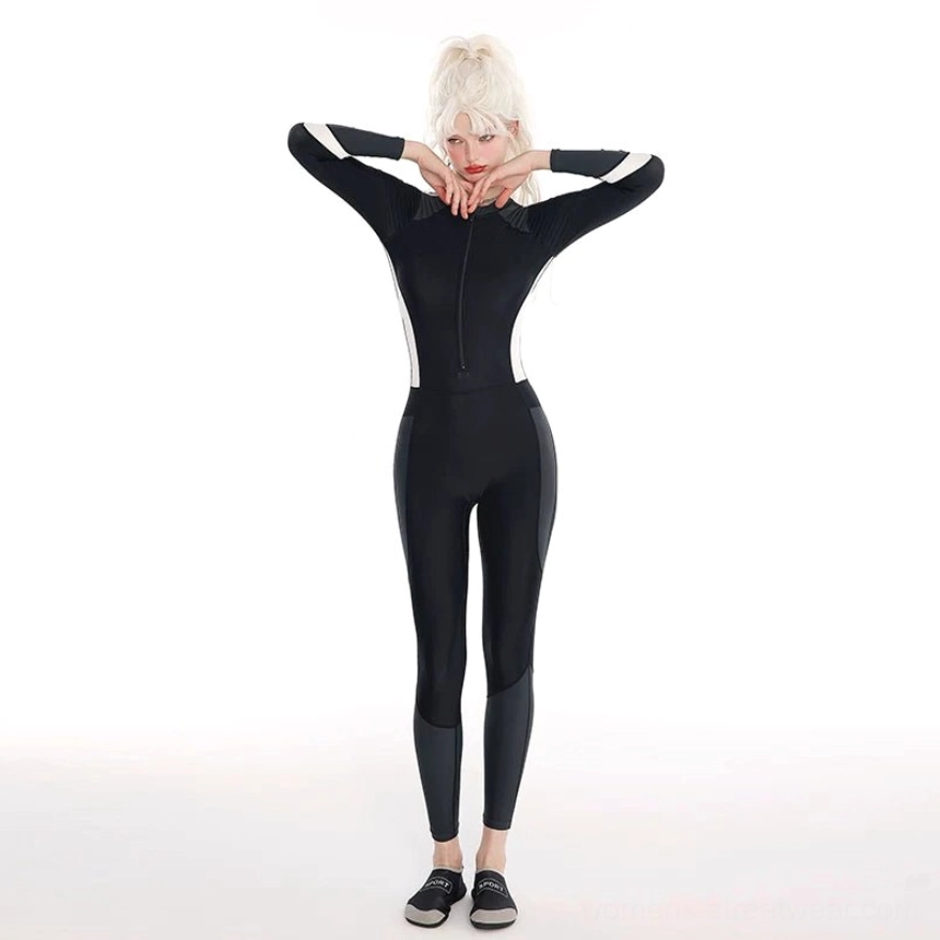 Full front view of black colorblock long-sleeve surf swim jumpsuit with white side panels, high neck, half zip, and ankle-length legs