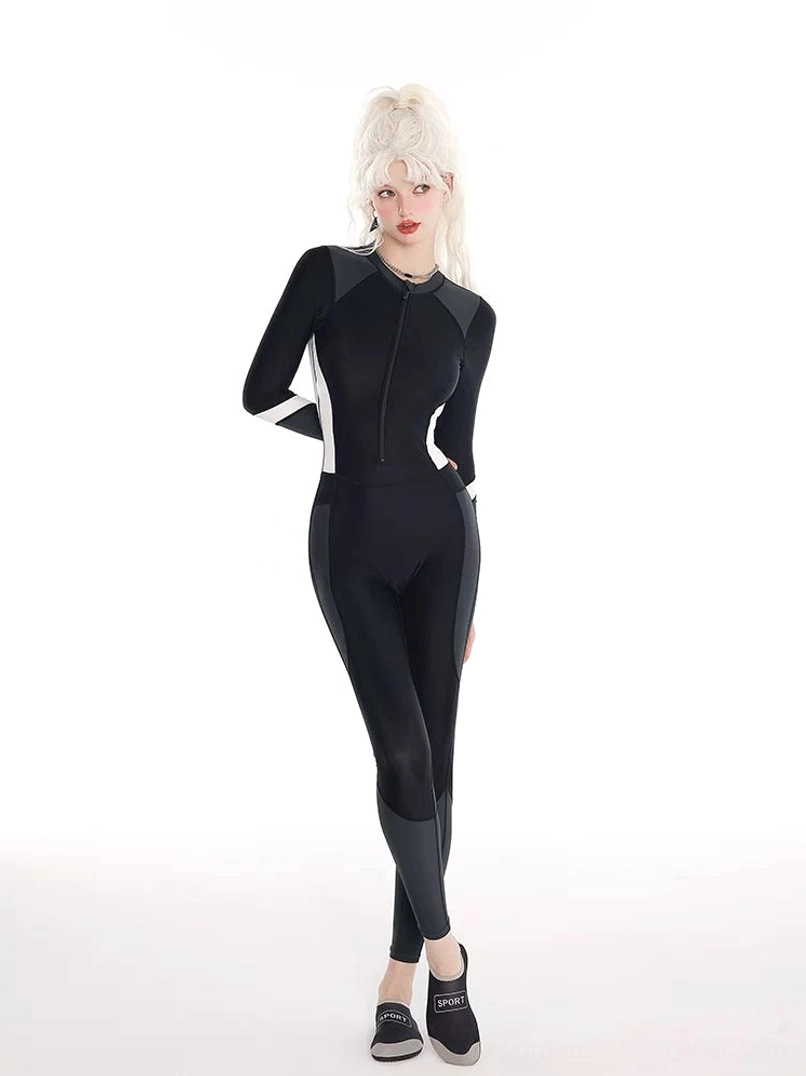 Three-quarter front view of black long-sleeve one-piece rash guard swim jumpsuit with charcoal legs and white sleeve stripe accents