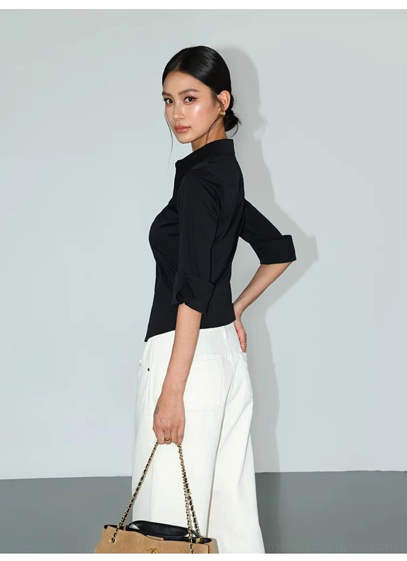 Rear three-quarter view of black contour curve tailored button-up shirt with curved hem and rolled sleeves