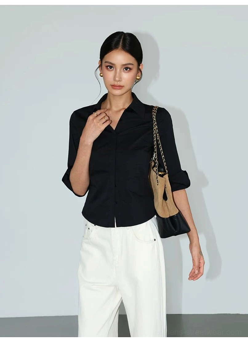 Black fitted contour curve button-up shirt with pointed collar and waist shaping styled with chain shoulder bag