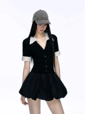 Front half-body view of black button-front contrast collar bubble hem mini dress styled with a gray baseball cap