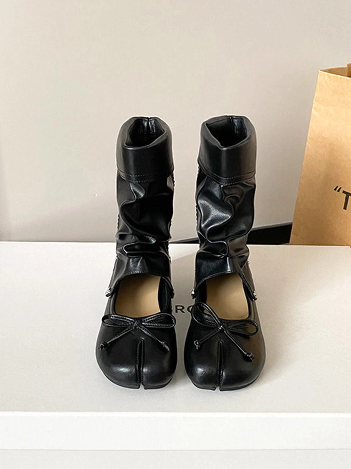 Front product view of black convertible tabi ballet sandal boots with split toe, bow and slouchy studded shaft