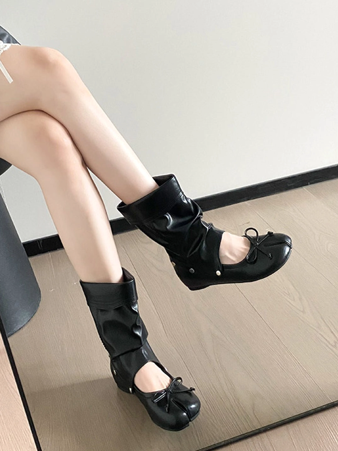 Overhead view of black tabi ballet boots worn with a crinkled detachable shaft, split toe and bow accents
