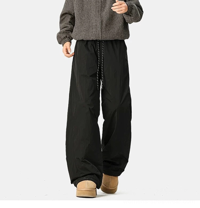 Black convertible wide-leg pants shown while walking, highlighting the fluid drape, relaxed fit, and crinkled streetwear shell