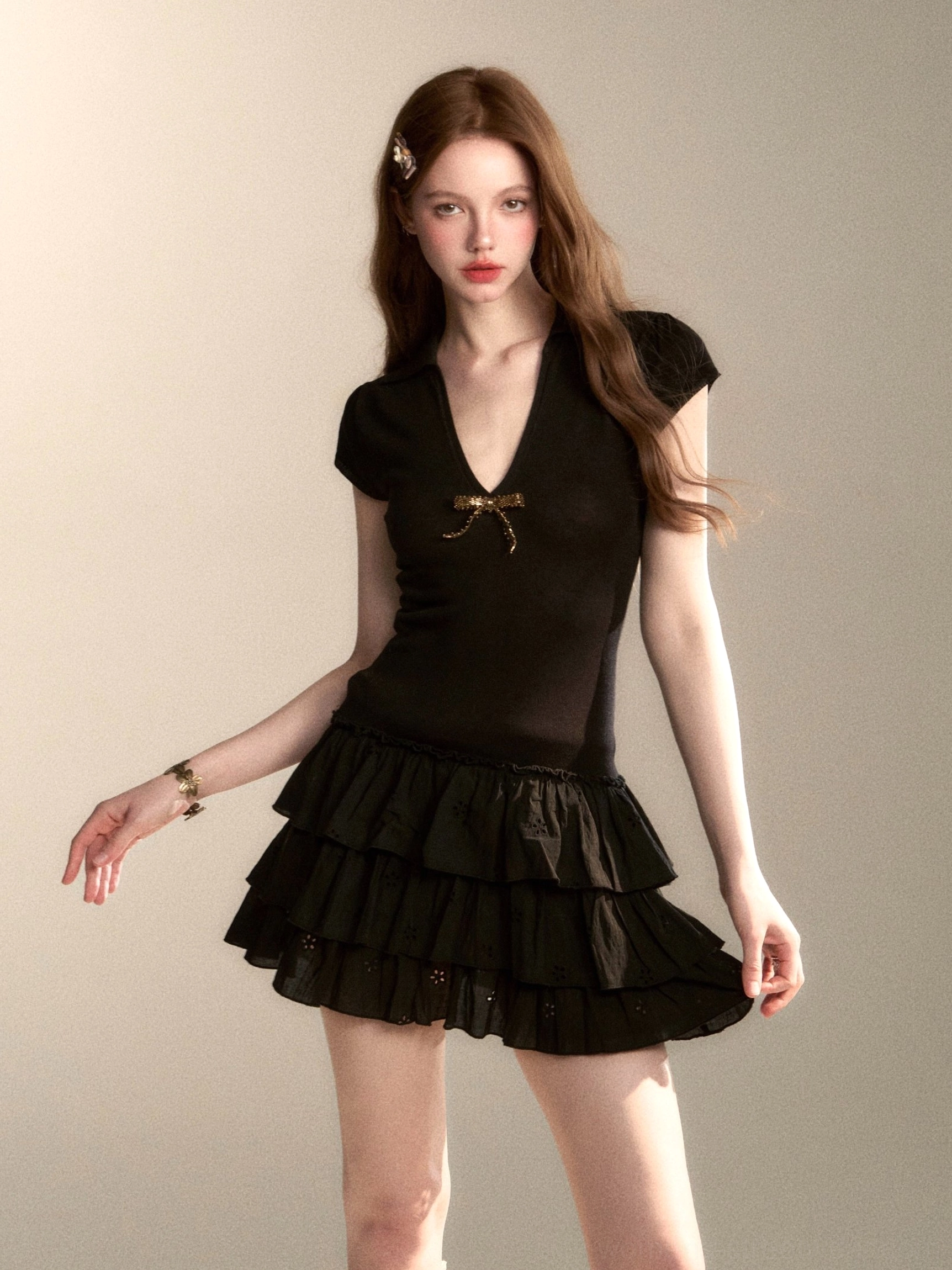 Black coquette mini dress with cap sleeves, chest bow, V-neckline, and tiered ruffle skirt side front view