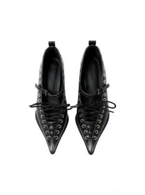 Front studio view of black corset lace pointed Mary Jane wedge pumps with silver metal eyelets, buckle ankle straps, and sharply pointed toes