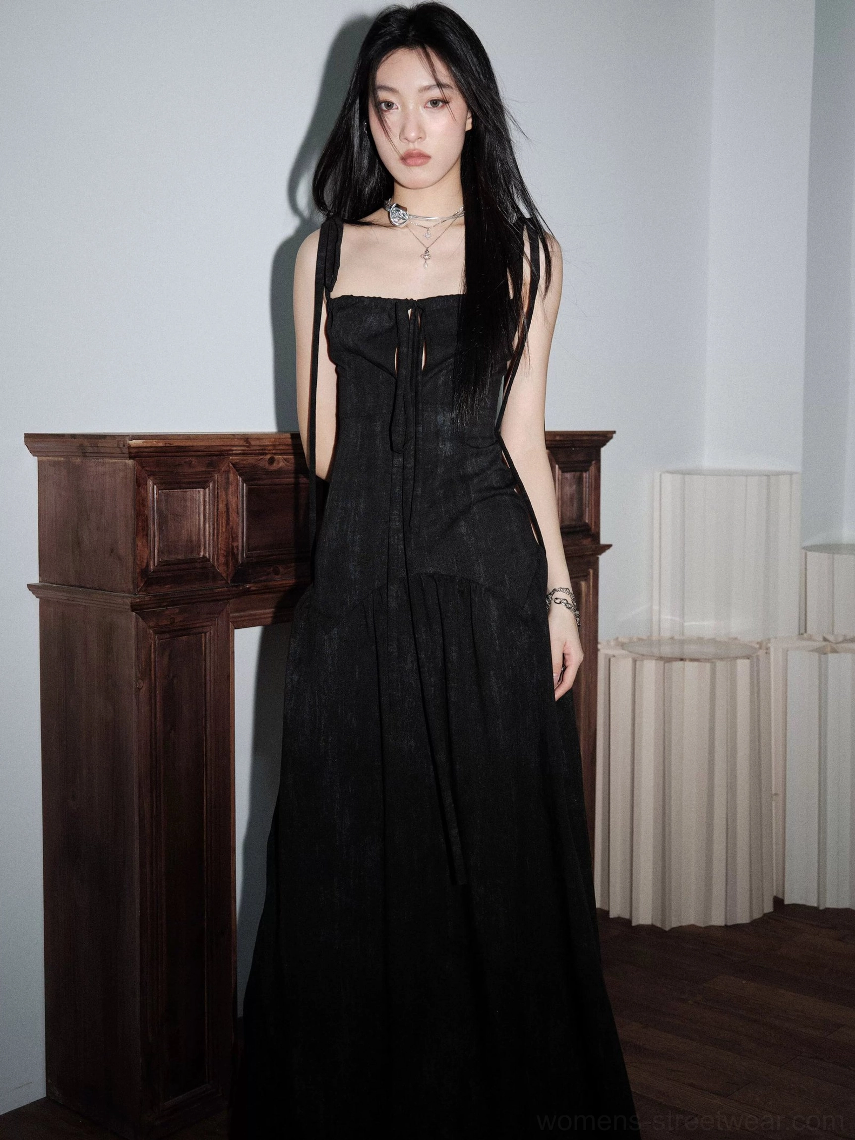Three-quarter view of a black corset maxi dress with square neckline, front lace-up detail, fitted waist, and dramatic flowing skirt