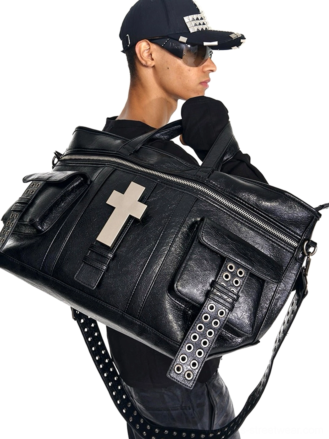 Streetwear model wearing black distressed leather crossbody tote bag with silver cross ornament and adjustable eyelet-studded shoulder strap
