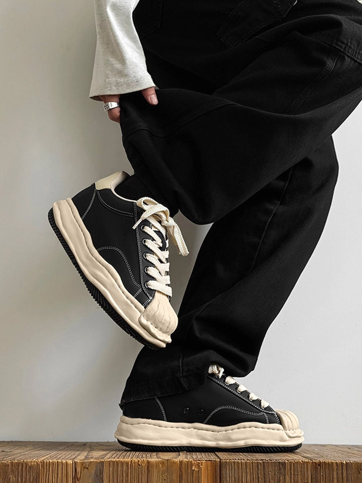 Black and cream height-boosting platform court sneakers with frayed contrast panels and lace-up low-top design