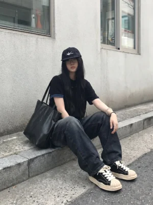 Black cream platform sneakers styled with loose dark denim and all-black streetwear on concrete steps