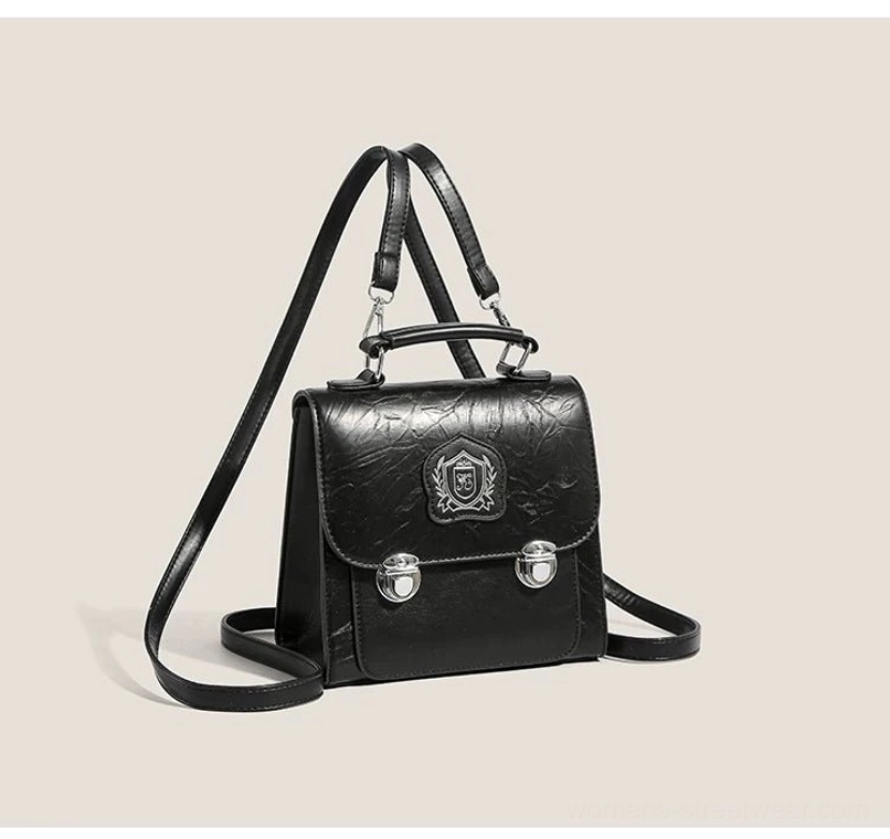 Black crested mini satchel bag in textured crinkle PU with silver hardware, front flap, top handle, and adjustable crossbody strap