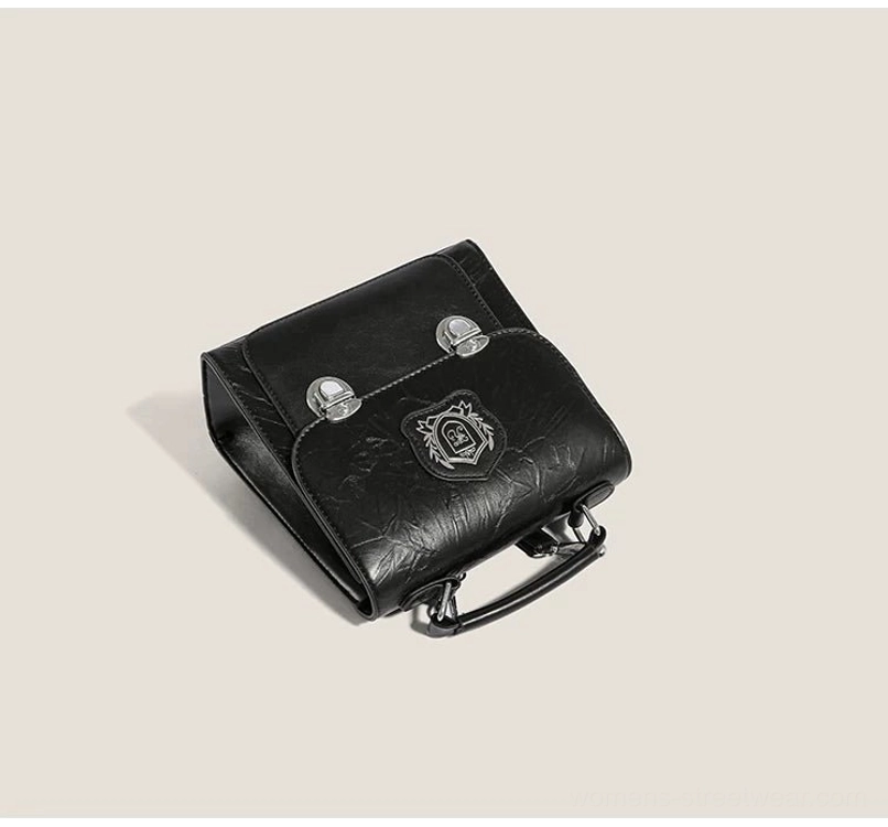 Overhead view of black crested crinkle PU mini satchel showing silver hardware, structured shape, and protective bottom studs