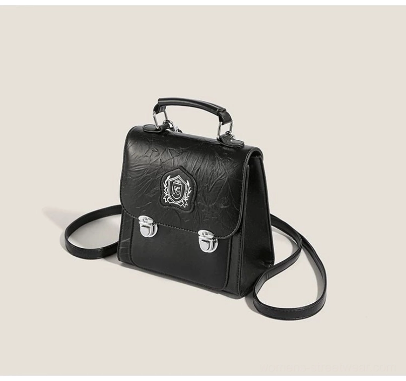 Black crinkle PU crested mini satchel crossbody bag with silver buckles, top handle, and detachable shoulder strap front view