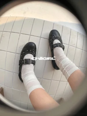 Top mirror view of black crinkled studded Mary Jane ballet flats styled with white crew socks